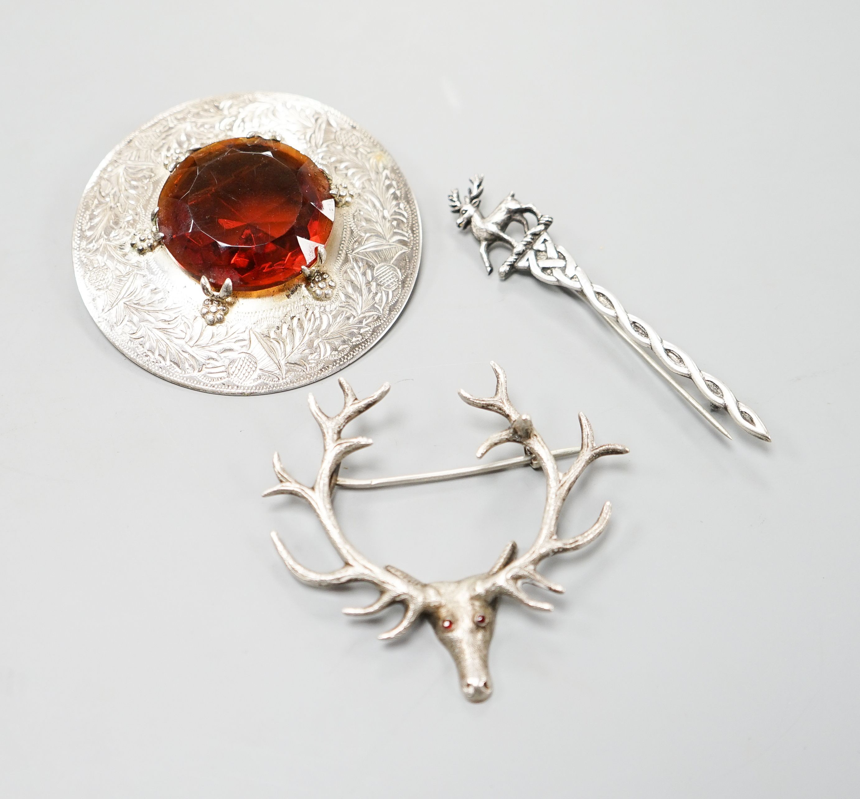 A Scottish silver and paste set circular brooch, Glasgow, 1952, together with a Scottish silver brooch, with stag terminal and one other metal stag head brooch.